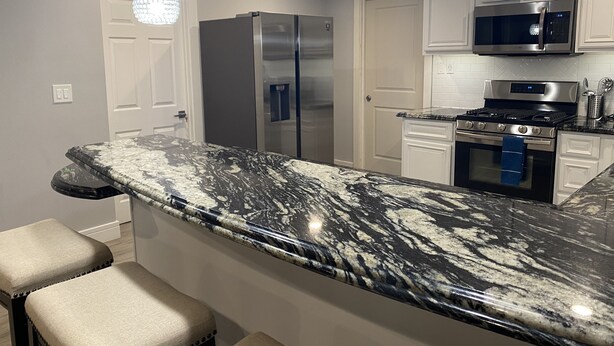 Una cocina con encimera de mármol, electrodomésticos de acero inoxidable e iluminación colgante.