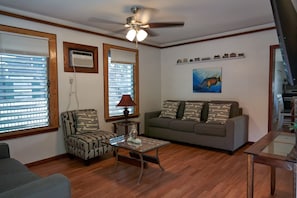 A living room with a ceiling fan, a sofa, a patterned armchair, a coffee table, and a painting on the wall. - Quiet Conch House in Historic District (Key West)