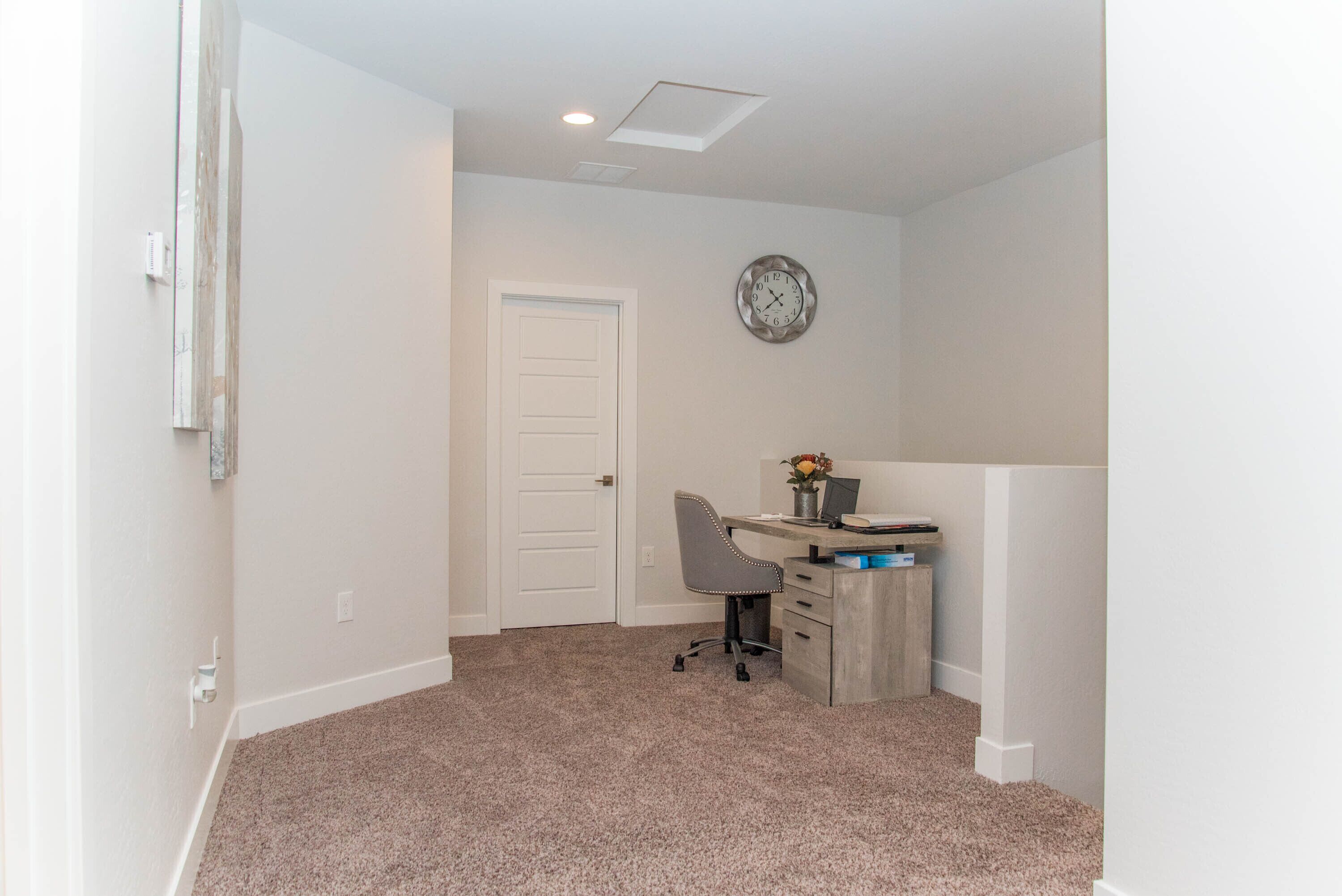 A small, clean room with a desk, chair, and a clock on the wall.