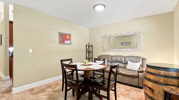 Un coin repas comprenant une table et des chaises, un canapé, un miroir et un tonneau décoratif.