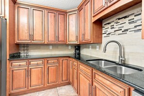 A kitchen with wooden cabinets, a stainless steel sink, and a coffee maker.