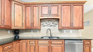 A kitchen with wooden cabinets, a stainless steel sink, and a tiled backsplash. - 3 min drive to the beach, walking distance to downtown, 5 miles from Destin! (Fort Walton Beach)