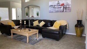 A living room with a black leather sofa, a wooden coffee table, and a large vase. - 15 minutes to strip !!! Vegas getaway (N las vegas)