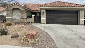 A single-story house with a tiled roof, a garage, and a landscaped front yard with rocks and sparse vegetation. - 15 minutes to strip !!! Vegas getaway (N las vegas)