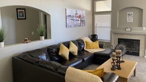 A living room with a black leather sectional sofa, a wooden coffee table, a fireplace, and a framed picture on the wall. - 15 minutes to strip !!! Vegas getaway (N las vegas)