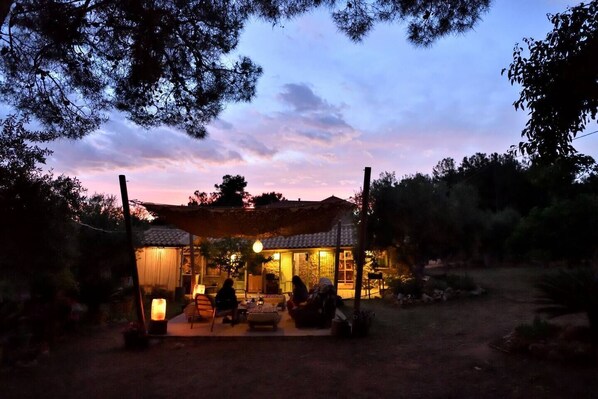 A traditional house with a tiled roof, a covered patio, and a well-lit interior. - Cocoon Tent in an Olive Grove (Marathopoli)