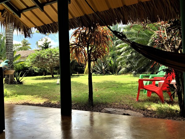 A covered outdoor area with a concrete floor, a hammock, and green plastic chairs. - La Casita! (Las Galeras)