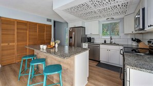 Une cuisine moderne dotée d’un îlot central, de meubles en bois et d’un panneau décoratif au plafond.