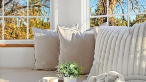 A cozy seating area with a cushioned bench, a potted plant, and a tray with a cup and saucer. - Airhockey | Firepit | Pool Table | Hot Tub (Big Bear)