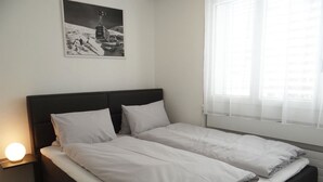 Un letto matrimoniale con biancheria da letto bianca in una stanza con finestra e un quadro appeso al muro.