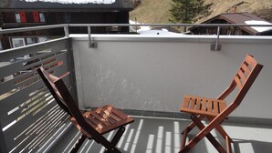Un balcone con due sedie di legno e un corrimano in metallo.