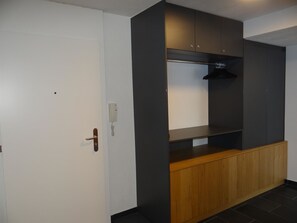 Una habitación con una puerta blanca, un armario de madera y una estantería oscura.