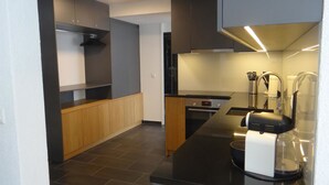 Una cucina moderna con mobili scuri, un piano di lavoro in legno e un forno integrato.