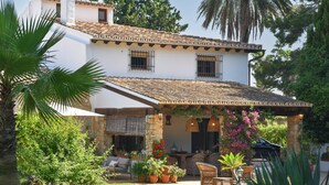 A house with a patio area featuring outdoor furniture, a stone wall, and potted plants.