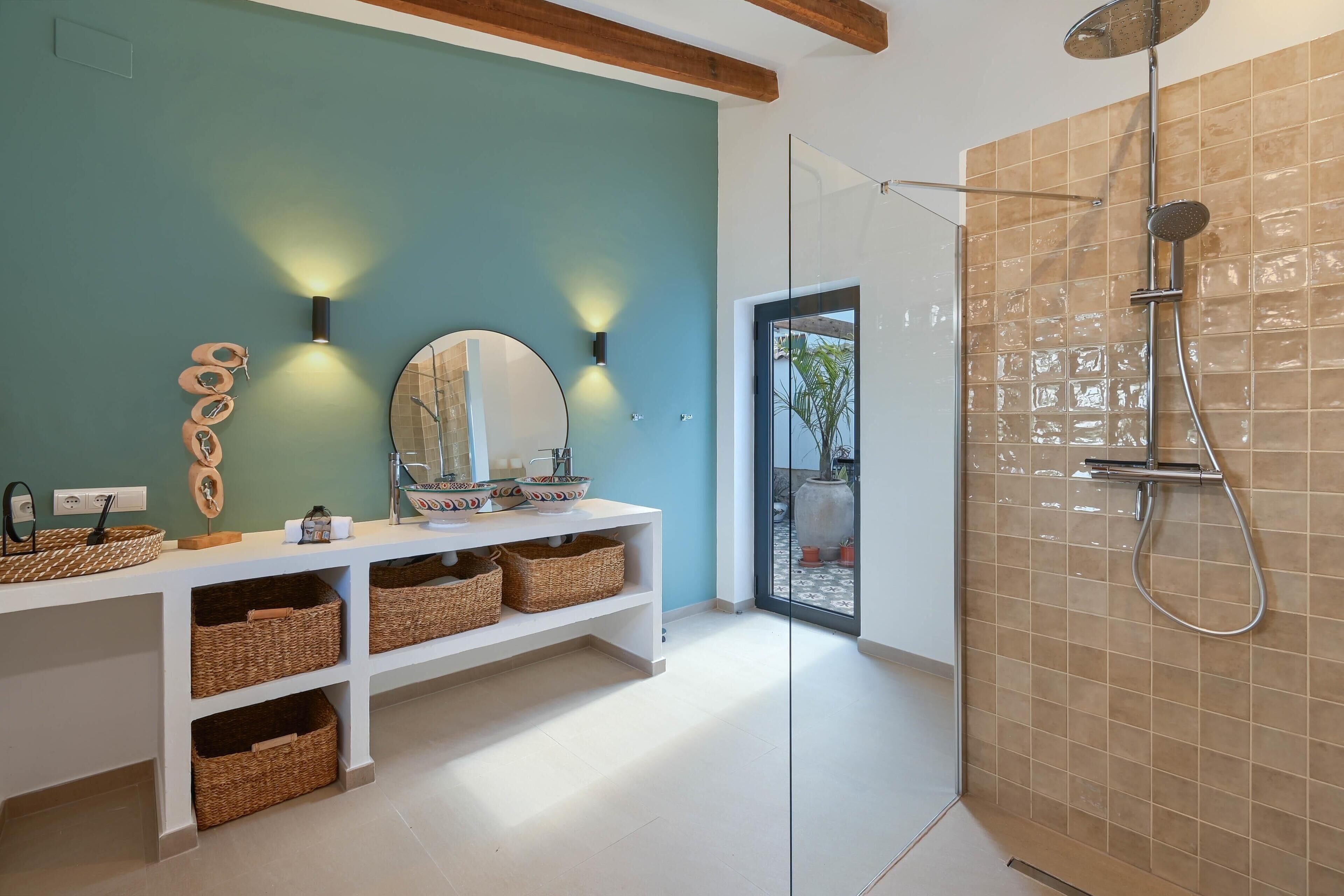 A modern bathroom with a glass shower enclosure, a white vanity with wicker baskets, and wall-mounted lighting.