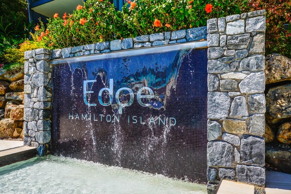 A stone wall with a water feature and the text "Edge Hamilton Island". - Edge 10 - Magnificent Views! (Hamilton Island)