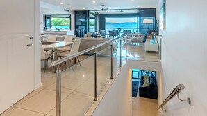 A spacious living area with a glass railing, a dining area, and a view of the sea. - Edge 10 - Magnificent Views! (Hamilton Island)