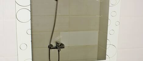 Un baño con un lavabo blanco, un espejo con diseños circulares y una ducha.