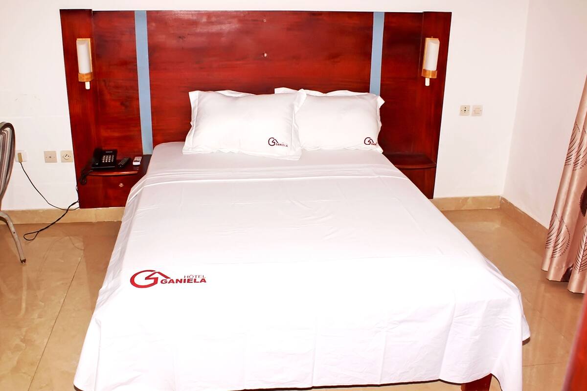 Ein Hotelzimmer mit einem großen Bett, zwei Nachttischen und einem Telefon.