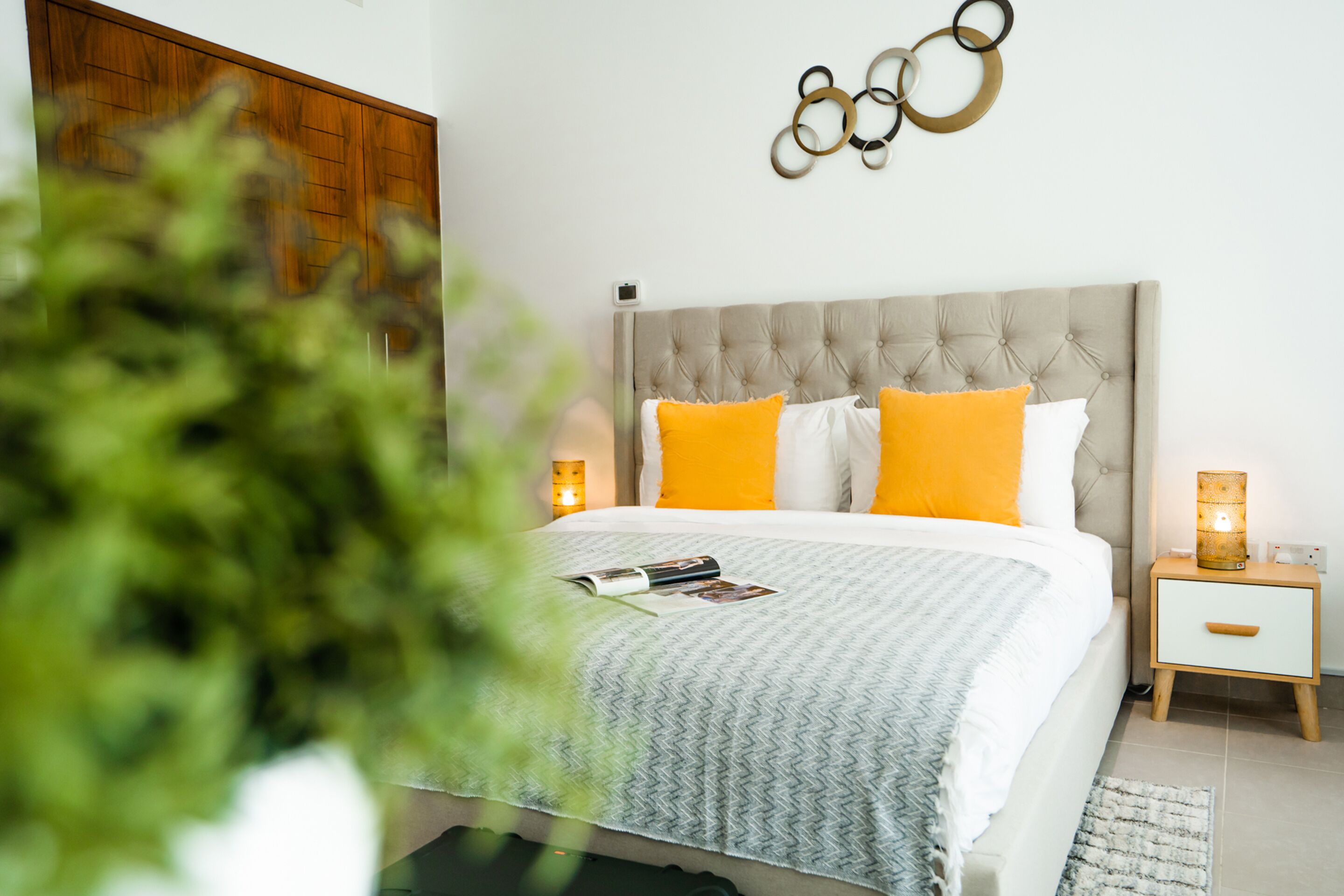 A bedroom with a tufted headboard, two bedside tables with lamps, and a bed with a patterned bedspread.