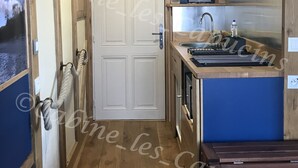 Een kleine keuken met houten kastjes, een inbouwoven en een spoelbak.