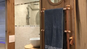 Een houten badkamer met een ronde spiegel, een wastafel en een handdoekhouder.