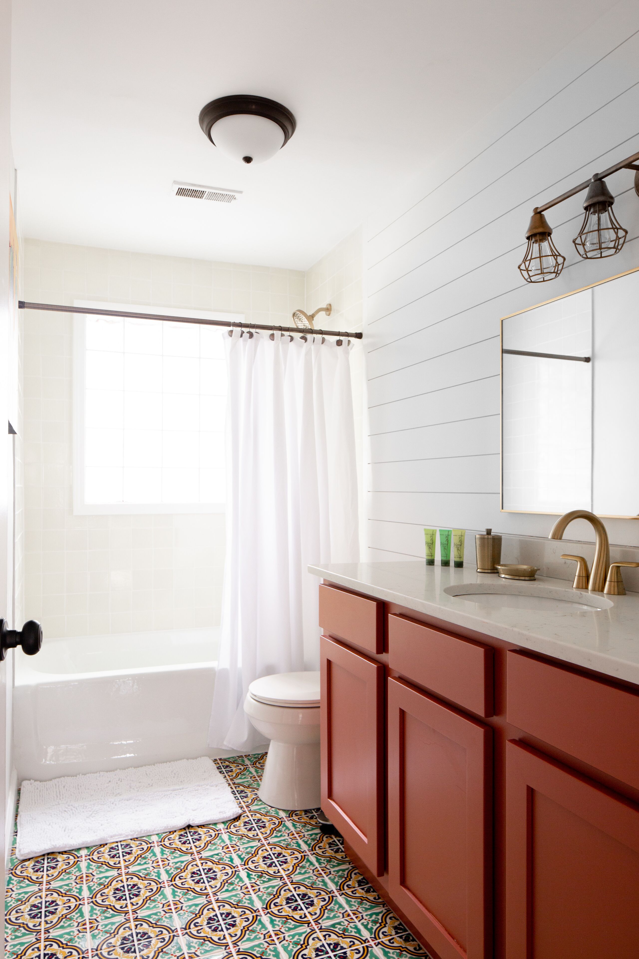 A bathroom with a bathtub, toilet, and a vanity with a mirror.