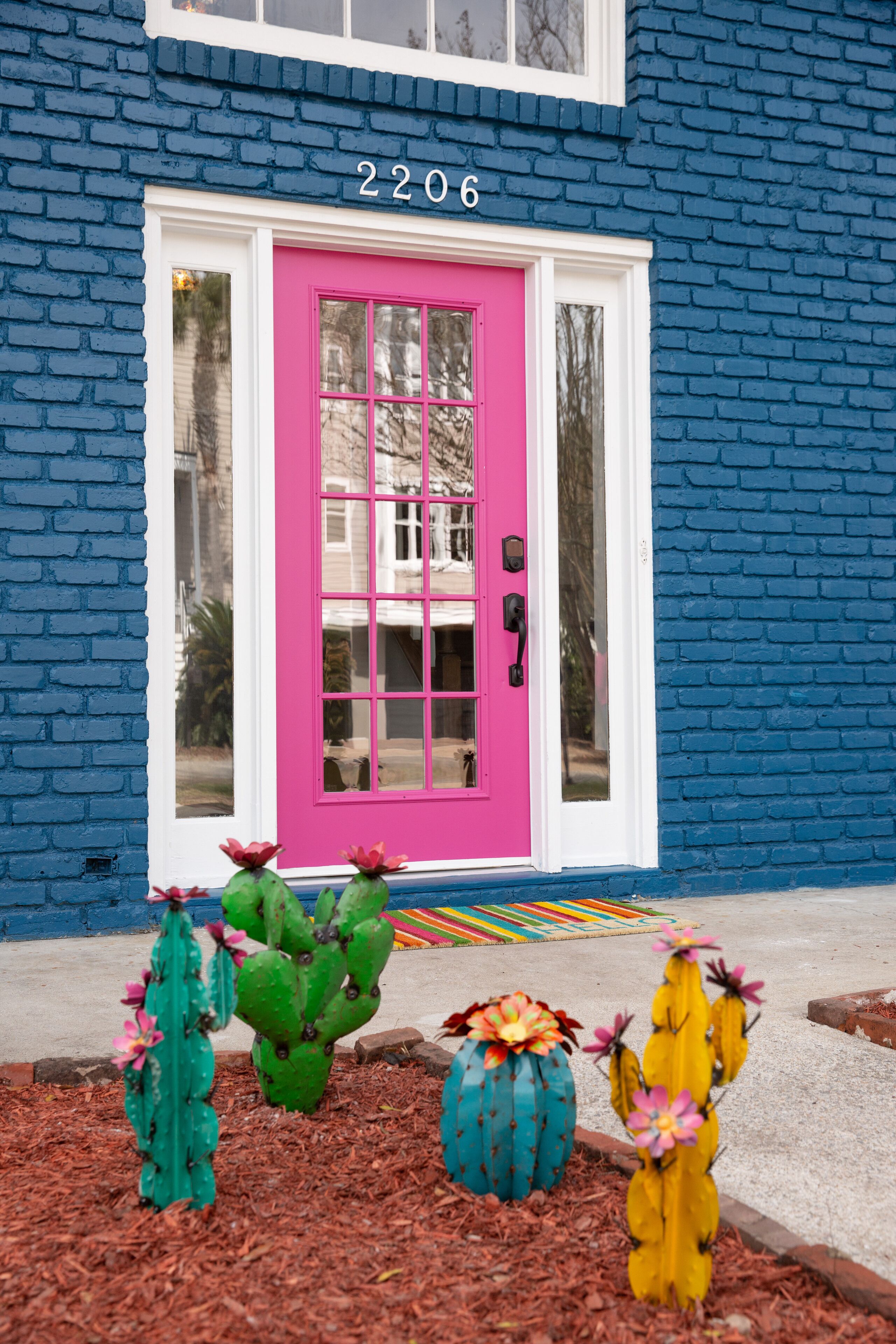 Una casa con fachada azul, puerta rosa y el número 2206.