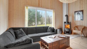A cozy living room with a gray sofa, a wooden coffee table, and a wood-burning stove. - Nice home in Rødby with sauna (Rødby)