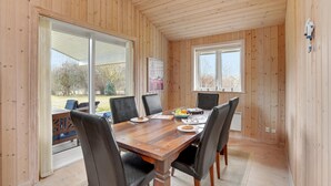 A wooden-paneled room with a large table, chairs, and a view of the outdoors. - Nice home in Rødby with sauna (Rødby)