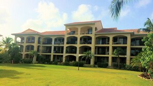A multi-story hotel with a central courtyard, balconies, and palm trees.