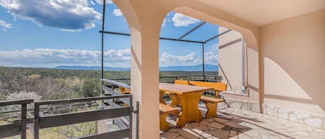 Un balcó amb taula i cadires de fusta, amb vista a un paisatge de muntanya.