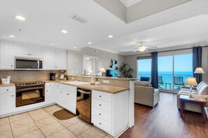 Enjoy cooking in the well-equipped kitchen with a central island, microwave, stove, and dishwasher. Relax in the adjacent living area with a sofa and coffee table, and take in the ocean view from the balcony.