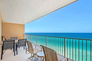 Enjoy the ocean view from this balcony with a table and chairs.