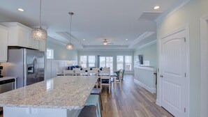 Een ruime keuken met een groot eiland, moderne apparaten en hanglampen.