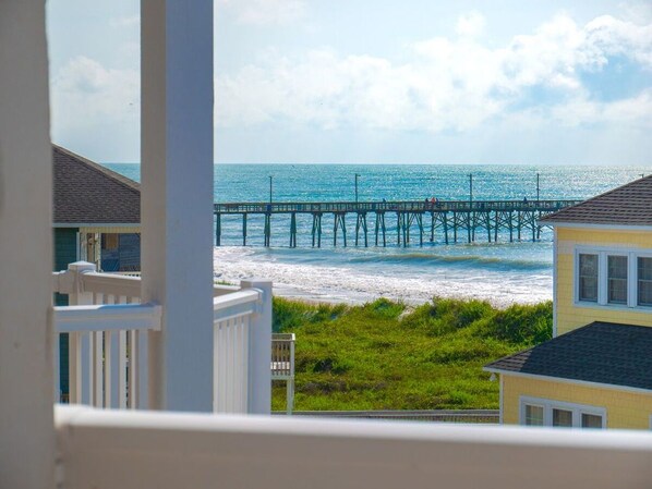 A coastal view with a pier extending into the sea, surrounded by buildings and grassy areas. - Modern oceanfront B Lot, 6 BR, 4.5 baths, Hot Tub, Elevator & Community Pool (North Topsail Beach)