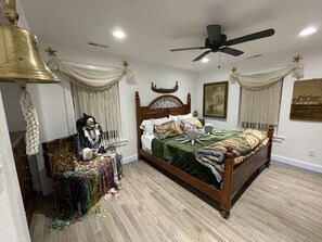 A bedroom with a large bed, a ceiling fan, and a decorative skull figure. - The Kraken House (Villas)