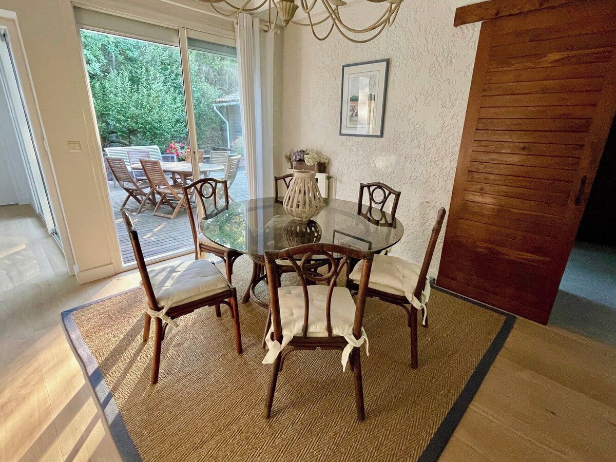 A dining area with a round glass table surrounded by wooden chairs with cushioned seats.
