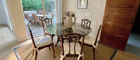 A dining area with a round glass table surrounded by wooden chairs with cushioned seats.