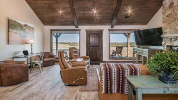 A spacious living room with leather recliners, a television, and a large window offering a view of the desert.