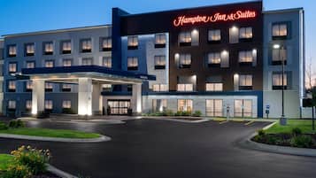 Un hotel Hampton Inn & Suites con entrada accesible, zona de estacionamiento techada y fachada bien iluminada.