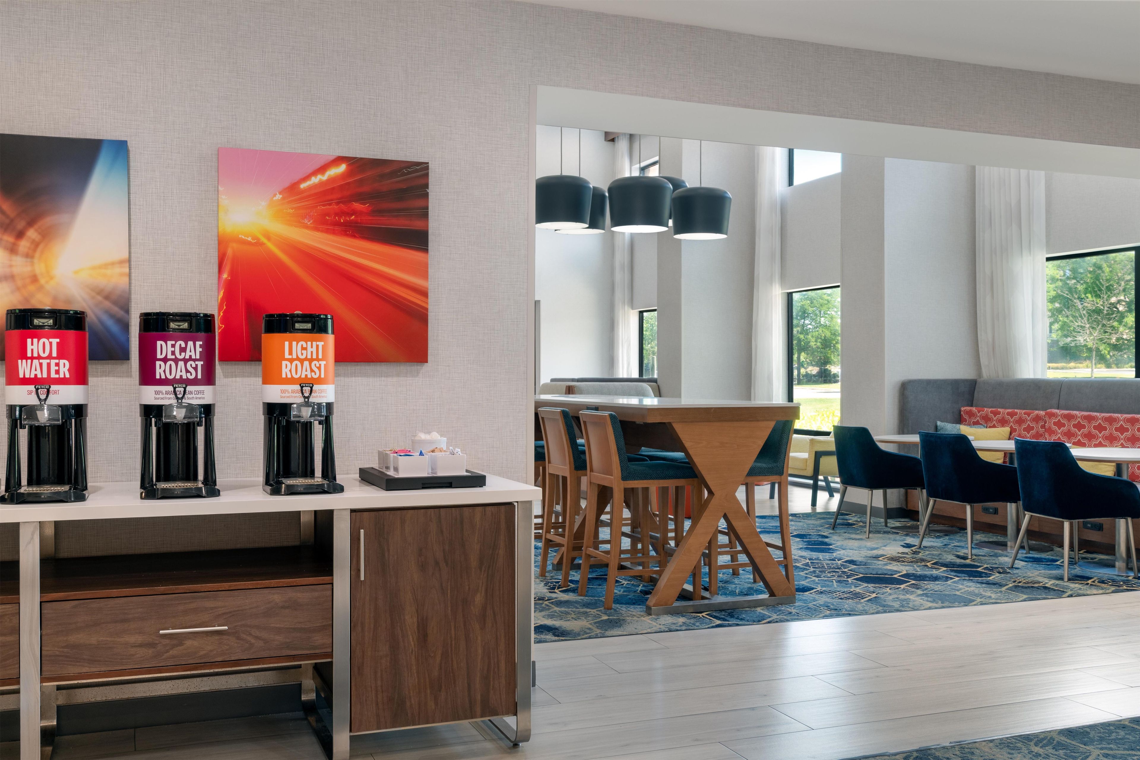 A hotel room with a coffee station, a dining area, and a view of the outdoors.