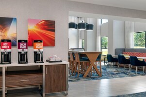 Habitación de hotel con estación de café, comedor y vistas al exterior.