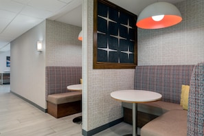 Een modern interieur met een zithoek, bestaande uit een bank en een tafel, een wand met een geometrisch patroon en een plafond met inbouwverlichting.