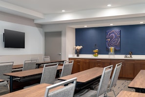 Uma sala de conferências com televisão de tela plana, uma parede azul decorativa e um objeto decorativo.