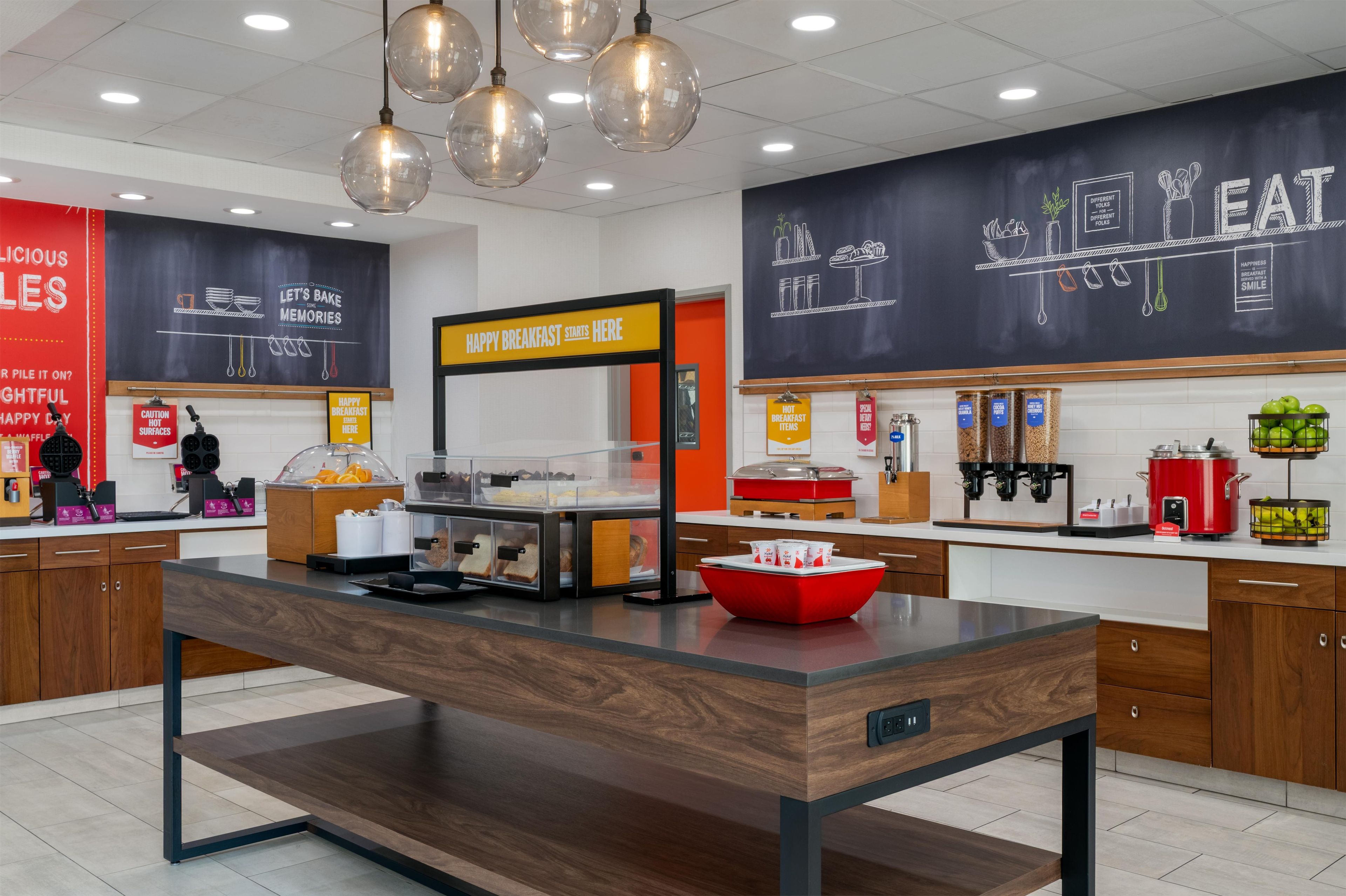 A breakfast area with a counter, food dispensers, and a chalkboard with breakfast-related drawings.