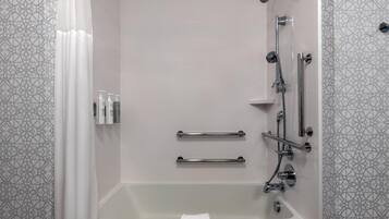 Ein modernes Badezimmer mit Badewanne, Dusche und Haltegriffen.