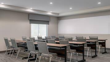 Uma sala de conferências com um amplo projetor, várias mesas e cadeiras.