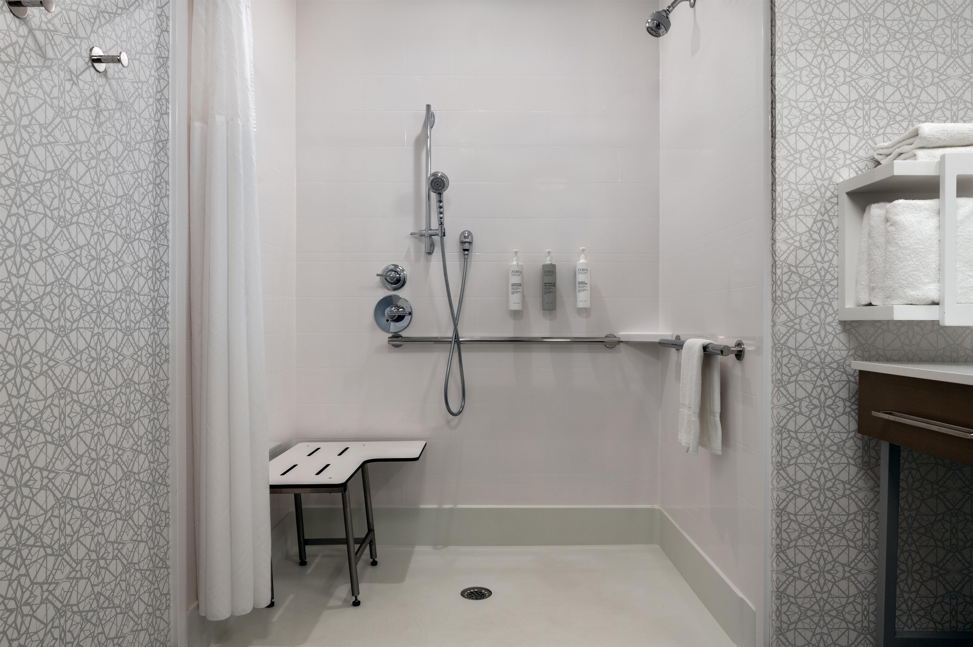 Una ducha con cabezal de ducha manual, un cabezal de ducha manual y un cabezal de ducha de pared. Hay un perchero con una toalla colgada.