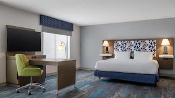 Ein Hotelzimmer mit einem Bett, einem Schreibtisch, einem Fernseher und einem Sessel.